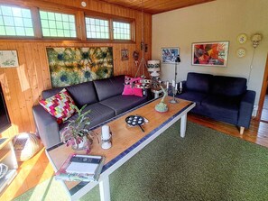 A cozy living room with a dark sofa, a coffee table, and a painting on the wall. - 5 Star Holiday Home in Knared (Knared)