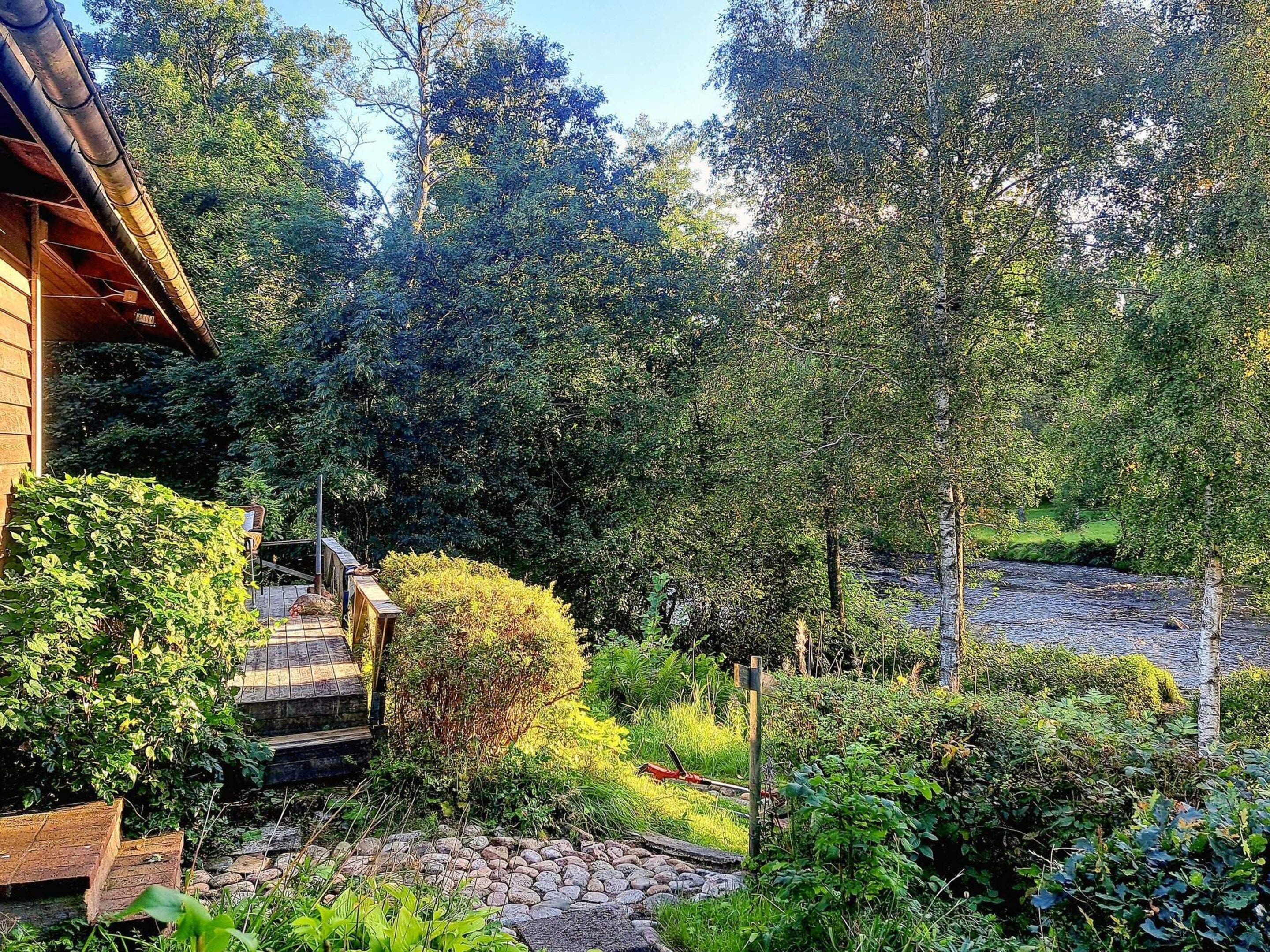A wooden house with a garden, a stone pathway, and a wooden fence.