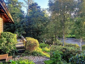 Una casa de madera con jardín, un sendero de piedra y una valla de madera.