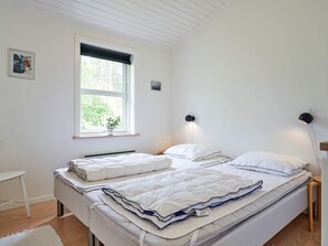 Une chambre à coucher avec un lit, des lampes de chevet, une fenêtre et une petite table.
