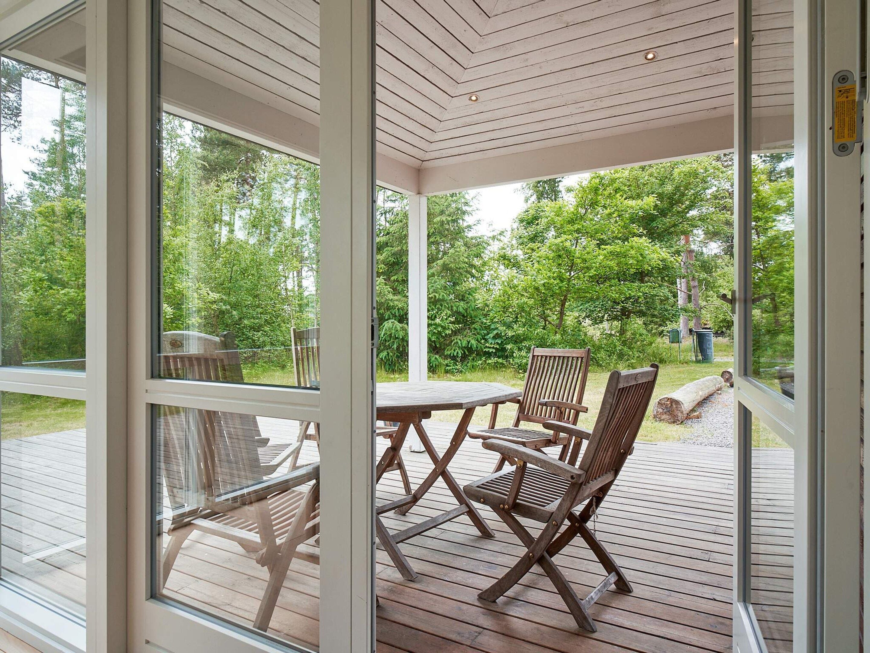 A covered outdoor area with a wooden deck, a table, and chairs.