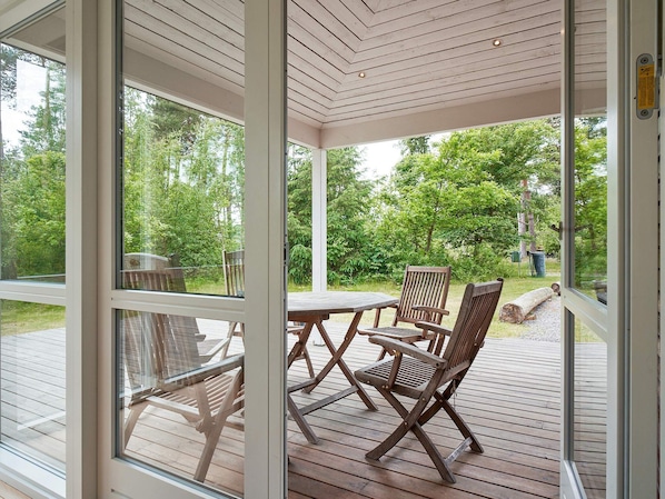 A covered outdoor area with a wooden deck, a table, and chairs.