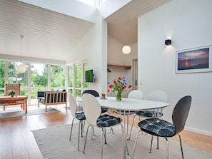 A modern dining area with a round table, white chairs, and a vase of flowers.