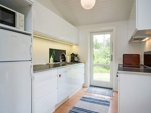 A modern kitchen with white cabinets, a built-in microwave, and a coffee maker on the counter. - 6 Person Holiday Home in Aakirkeby (Akirkeby)