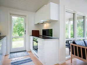 Une cuisine moderne équipée d’un four encastré, d’une cuisinière et d’un four à micro-ondes. Une fenêtre offre une vue sur l’extérieur.