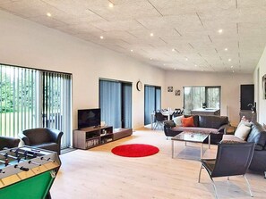 A modern living room with a foosball table, a television, and a dining area with a table and chairs. - 5 Star Holiday Home in Vaeggerlose (Vaeggerlose)