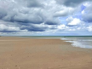 Une plage avec un large rivage sablonneux et un ciel nuageux.
