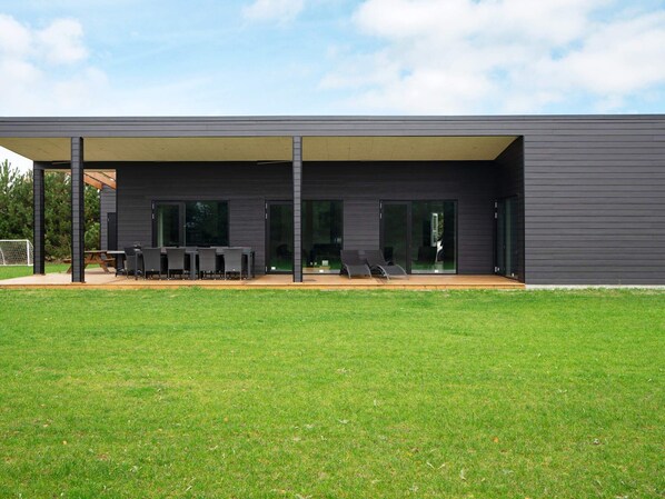 Une maison moderne dotée d’un patio couvert, d’un coin repas et d’une piscine.