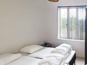 Une chambre à coucher avec un lit, une table de chevet et une fenêtre avec des stores.