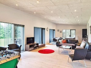 A modern living room with a foosball table, a television, and a dining area with chairs and a table. - 5 Star Holiday Home in Vaeggerlose (Vaeggerlose)