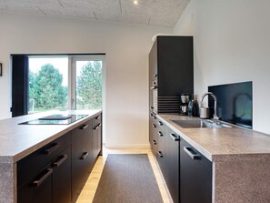 A modern kitchen with a large window, dark cabinetry, and a built-in oven. - 5 Star Holiday Home in Vaeggerlose (Vaeggerlose)