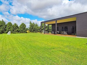 A modern house with a covered patio, a well-maintained lawn, and a soccer goal. - 5 Star Holiday Home in Vaeggerlose (Vaeggerlose)