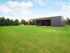 A modern building with a flat roof and large windows, surrounded by a well-maintained grassy area. - 5 Star Holiday Home in Vaeggerlose (Vaeggerlose)