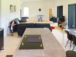 Un salon moderne comprenant un canapé d’angle, une table basse et un coin repas avec une table et des chaises.
