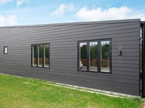 Un edificio moderno con techo plano, amplias ventanas y fachada oscura.