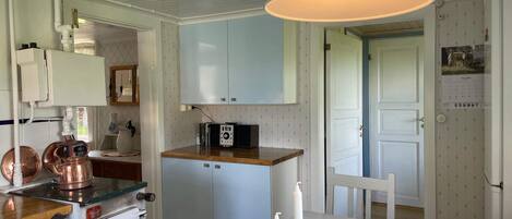 A kitchen with a microwave, a small refrigerator, and a wooden countertop.