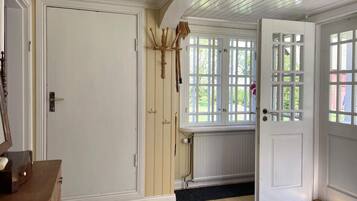 Una habitación con piso de madera, una puerta con ventana, un radiador y una alfombra pequeña.