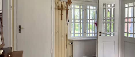 A room with a wooden floor, a door with a window, a radiator, and a small rug.