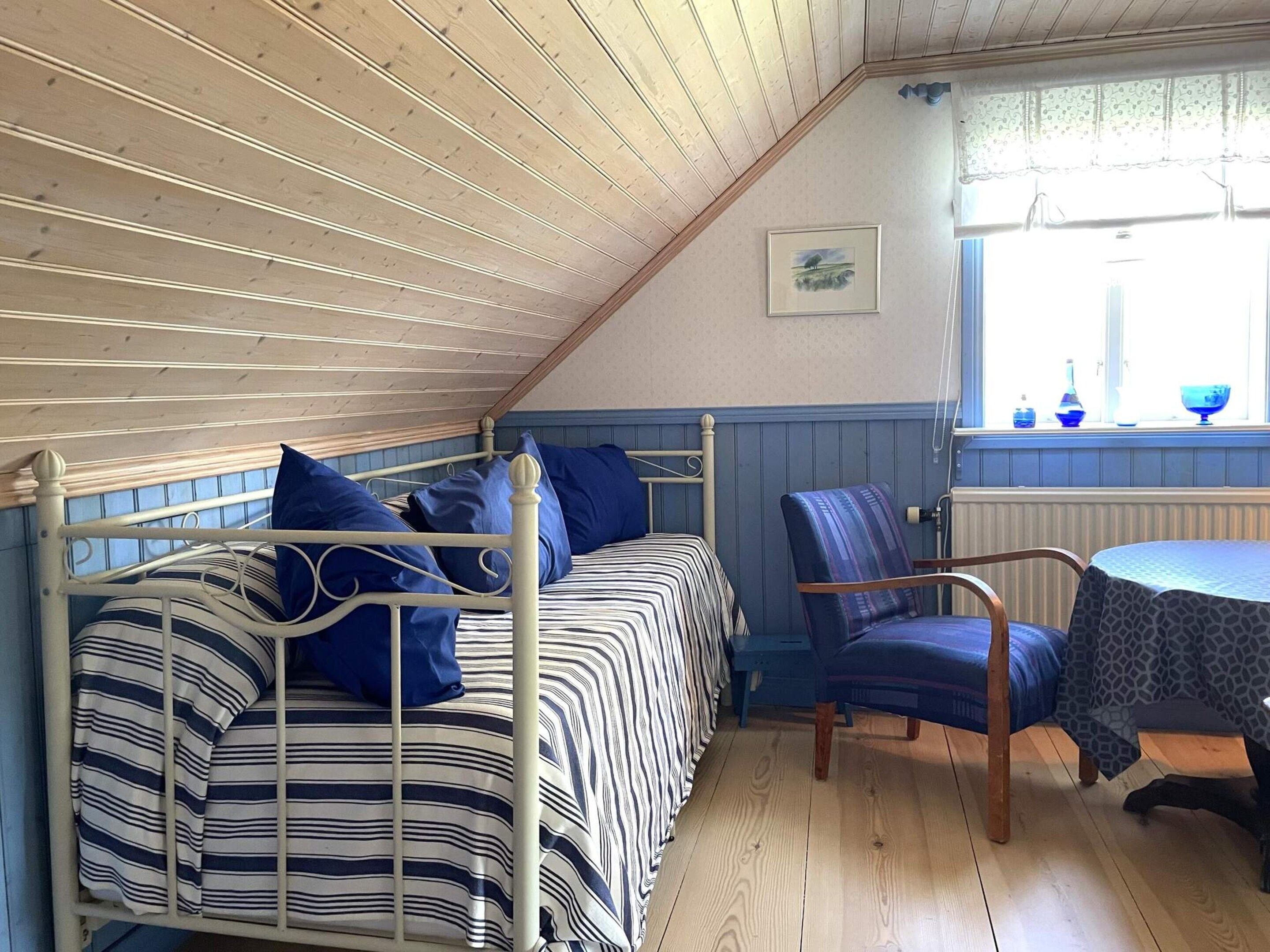 A room with two beds, a chair, a table, and a window with a view.