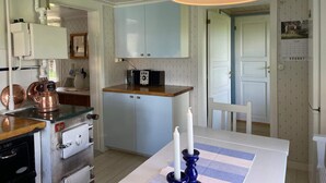Une cuisine compacte équipée d’un four à micro-ondes, d’un petit réfrigérateur et d’un plan de travail en bois.