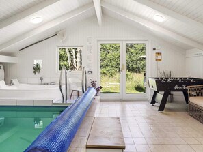 Un espace piscine doté d’un grand toboggan bleu, d’une table de baby-foot et d’un canapé installé au bord de la piscine.