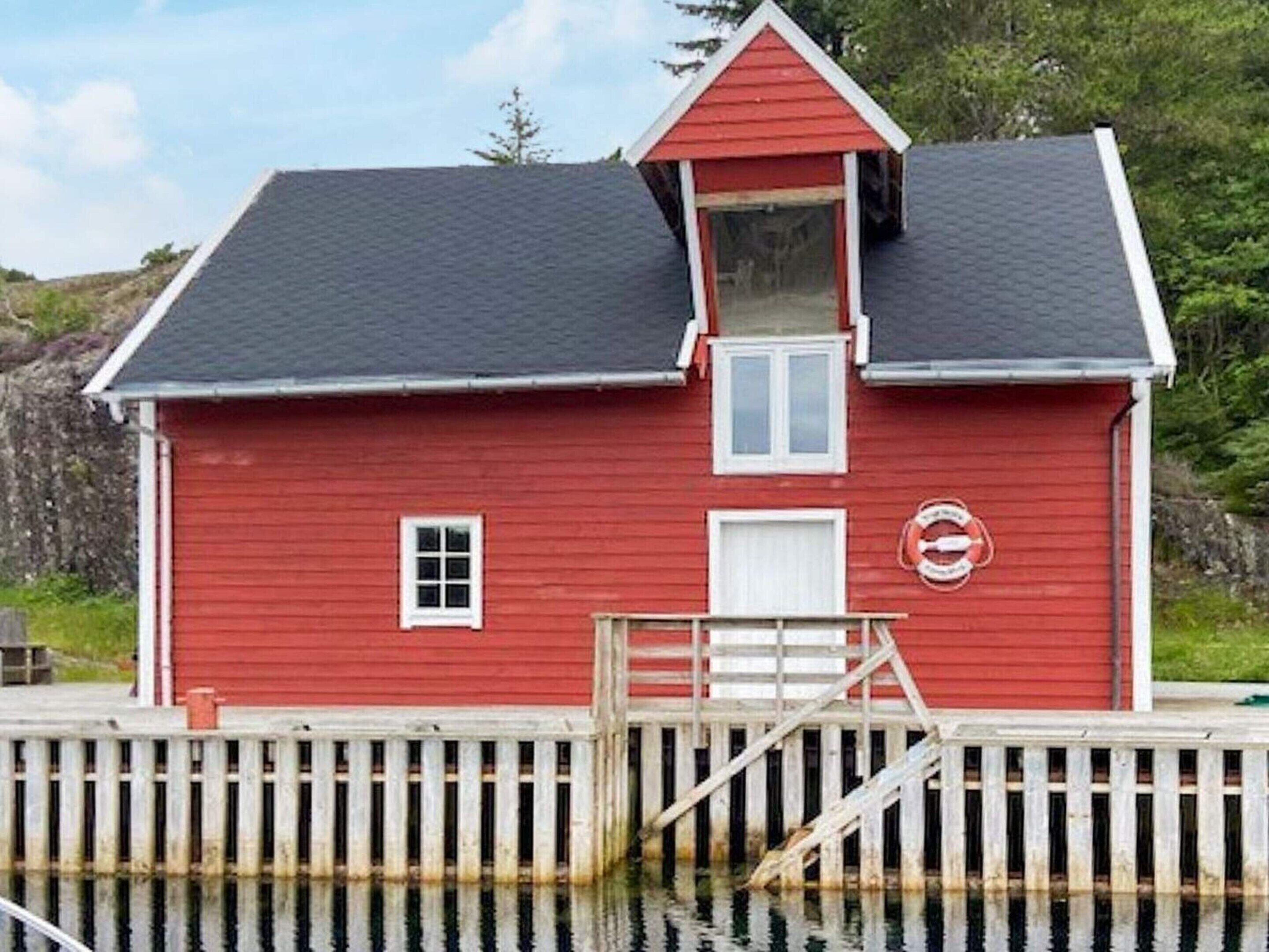 A red wooden building with a small balcony, a door, and a window.