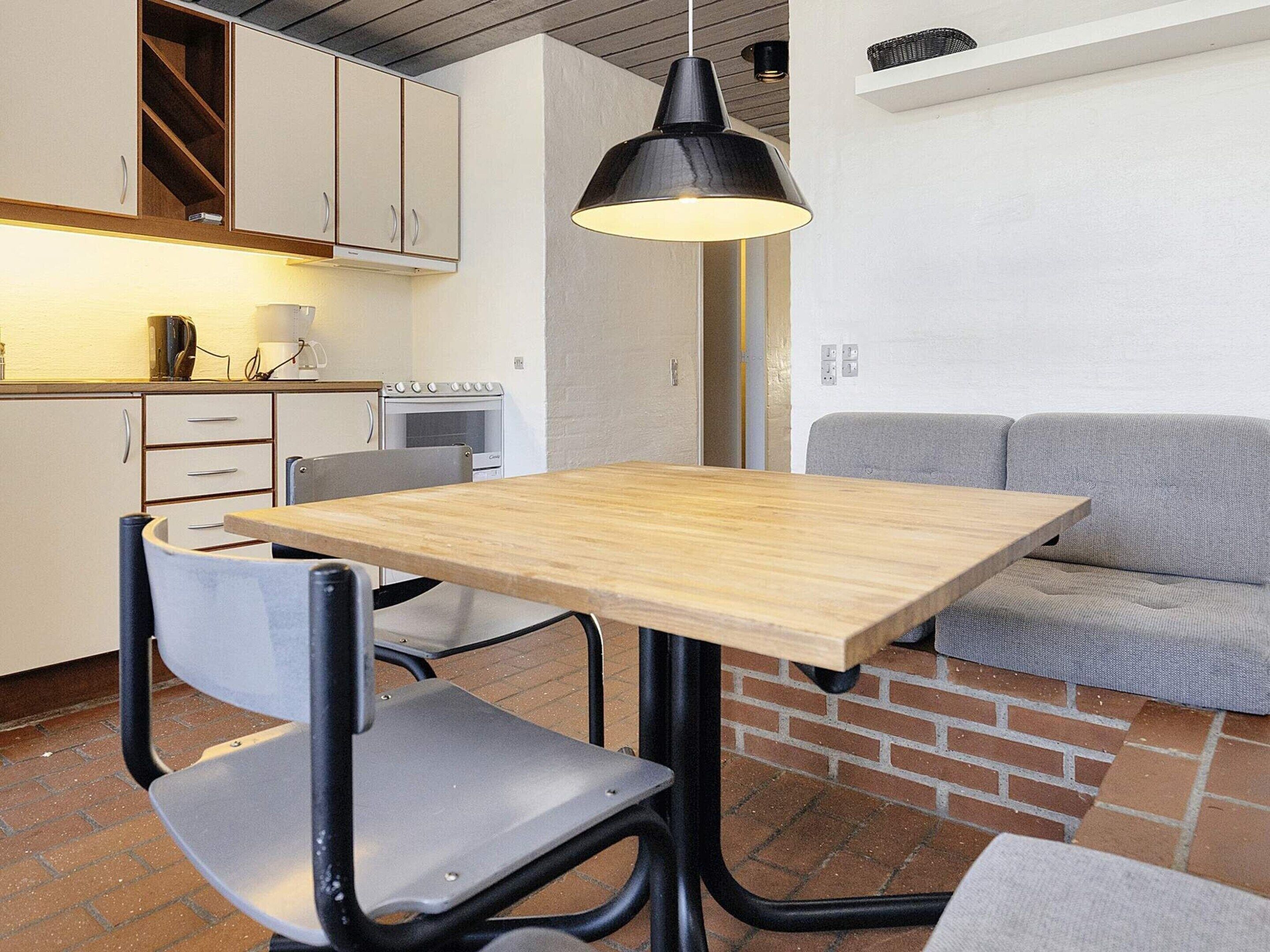 A compact kitchen with white cabinets, a stove, and a dining area with a wooden table and metal chairs.