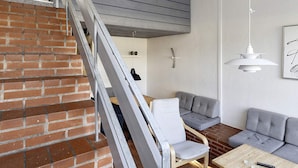 A modern living space with a brick staircase, grey sofa, and a wooden coffee table.