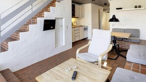 A modern living space with a staircase, a kitchen, a seating area with a table, and a sofa.