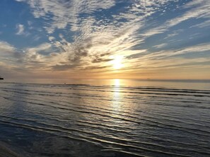A beach with the sun setting over the water, creating a calm and reflective surface. - 6 Person Holiday Home in Albaek (Aalbaek)