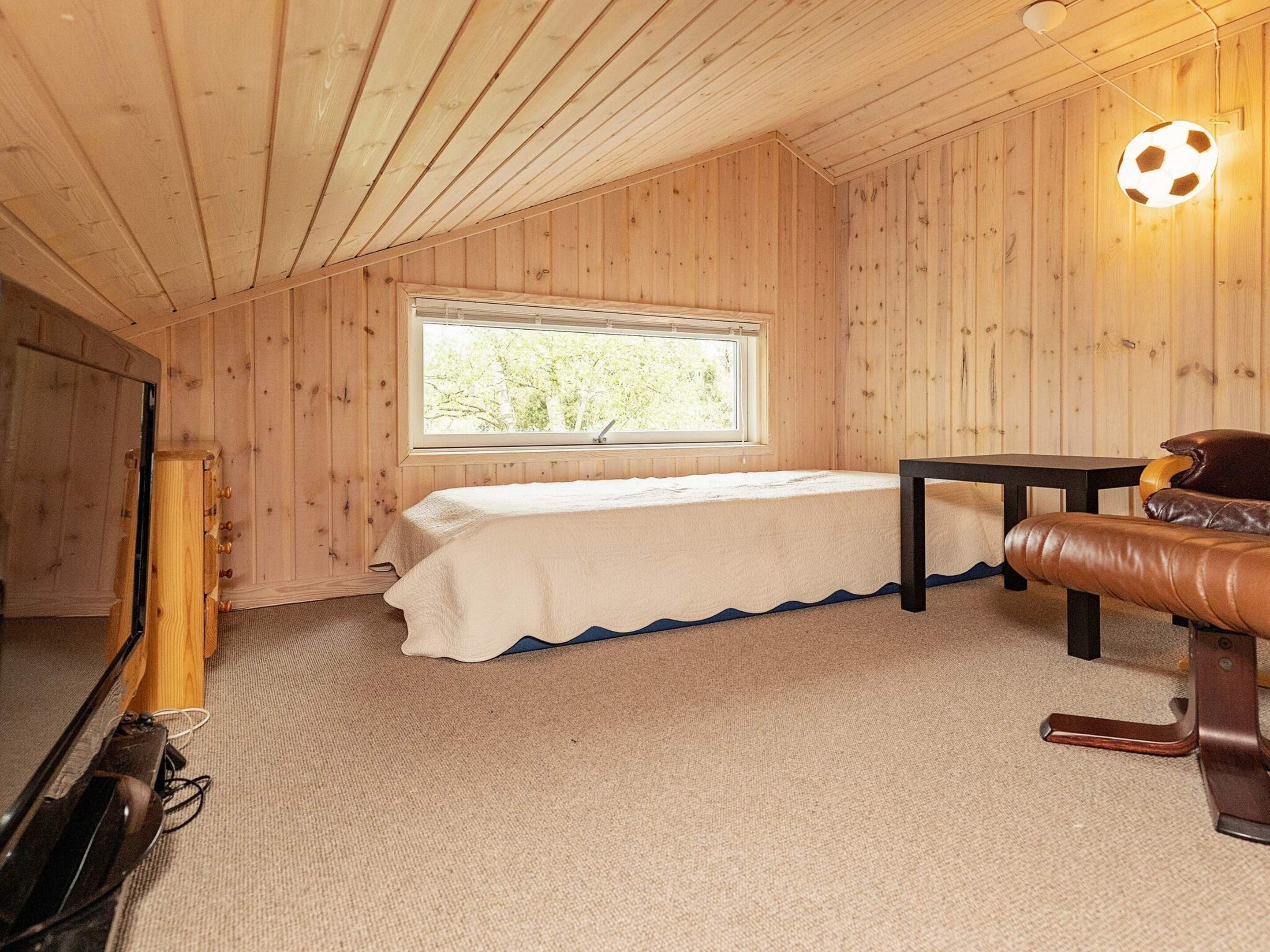 Een kamer met een bed, een tafel, een bank en een raam.