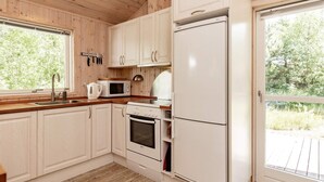 A kitchen with wooden cabinets, a microwave, a stove, and a refrigerator. - 6 Person Holiday Home in Albaek (Aalbaek)