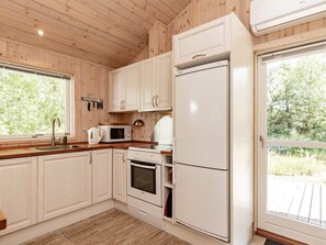 A kitchen with wooden cabinets, a microwave, a stove, and a refrigerator. - 6 Person Holiday Home in Albaek (Aalbaek)