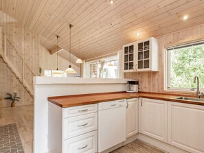 A kitchen with white cabinets, a wooden countertop, and a window with a view of greenery. - 6 Person Holiday Home in Albaek (Aalbaek)