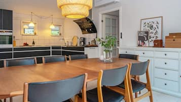 Una cocina moderna con comedor, que incluye una mesa de madera, sillas e iluminación colgante.
