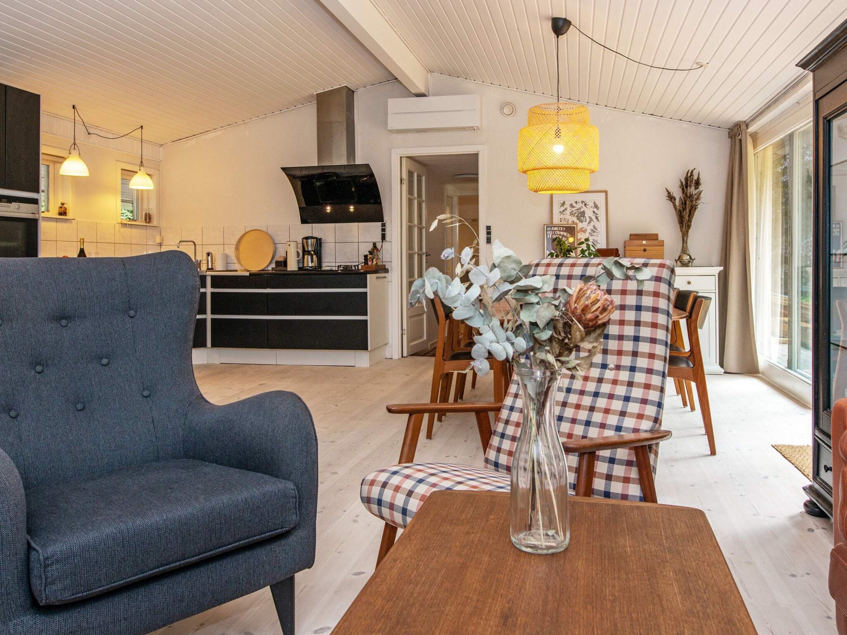 Ein modernes Wohnzimmer mit einem grauen Sofa, einem Holzesstisch und einer Vase mit Trockenblumen.