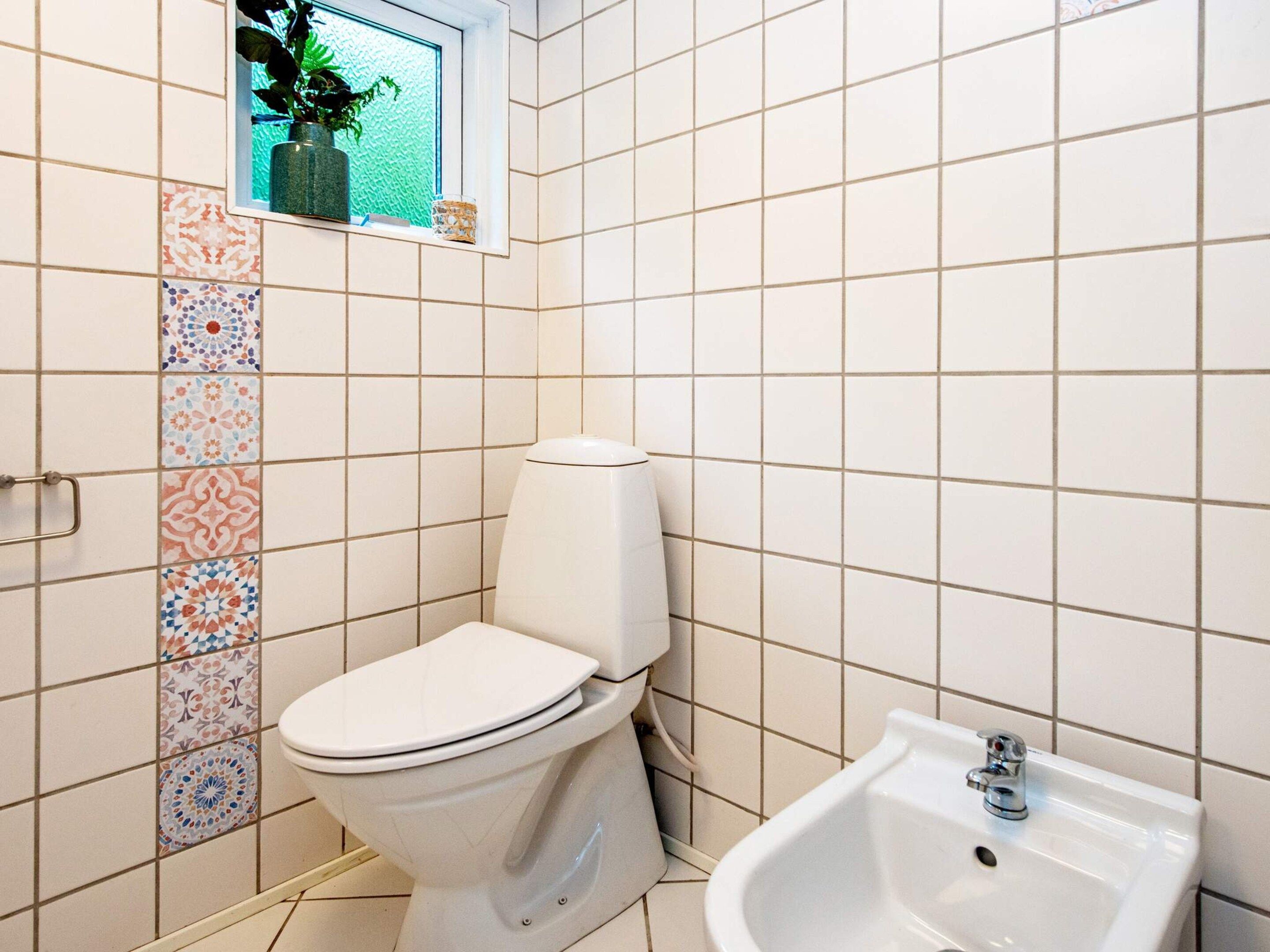 Un bagno con un WC, un bidet e una piccola finestra con una pianta.
