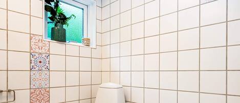 Un bagno con un WC, un bidet e una piccola finestra con una pianta.