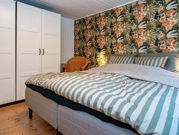 Une chambre à coucher avec un lit, une chaise, une armoire et un papier peint à motifs floraux.