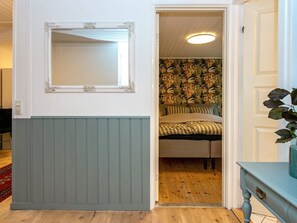A room with a bed, a mirror, and a door leading to another room.