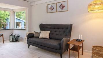 A cozy living room with a dark grey sofa, a small wooden side table with candles, and a woven basket.
