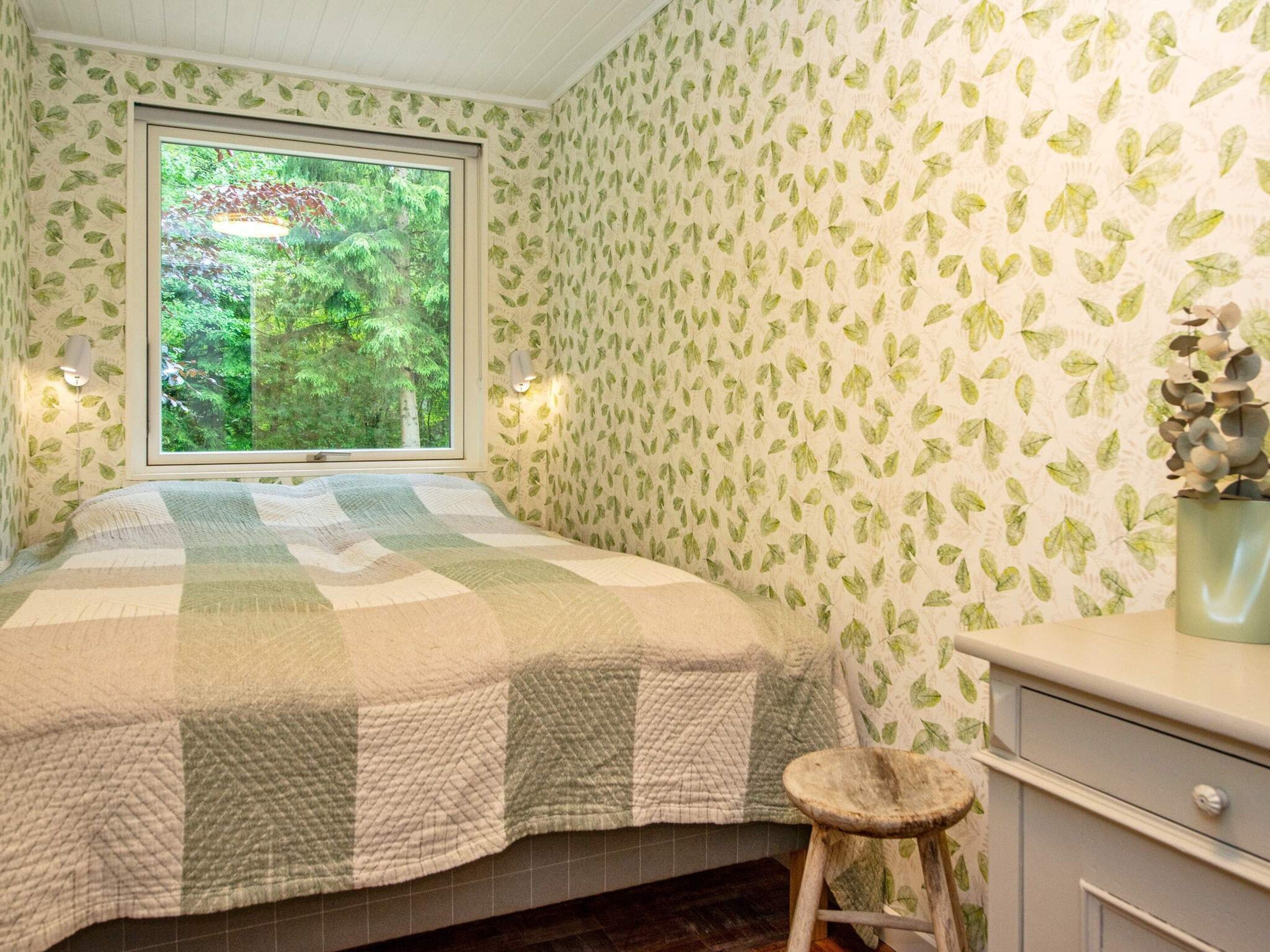 Une chambre à coucher avec un lit, une fenêtre, une commode et un tabouret.