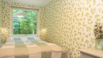 A bedroom with a bed, a window, a dresser, and a stool.
