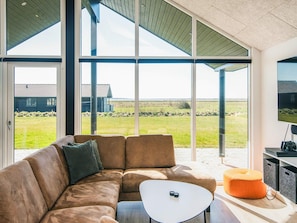 A modern living room with a large sectional sofa, a small coffee table, and a television on a stand.