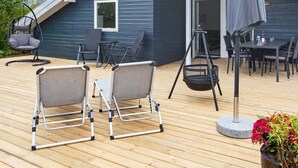 A deck with outdoor furniture, including chairs and a table, and a grill. - 4 Star Holiday Home in Sydals (Sydals)