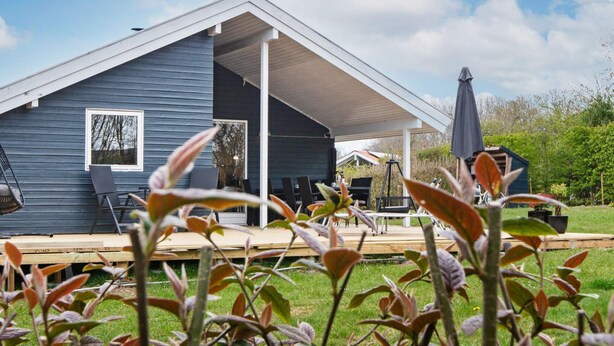 A house with a covered patio, a swing chair, and a table with chairs. - 4 Star Holiday Home in Sydals (Sydals)