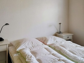 Una habitación sencilla con una cama, una mesita de noche y una lámpara.