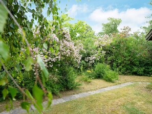 A garden with a stone pathway, various shrubs, and flowering plants. - 6 Person Holiday Home in Hojby (Hojby)