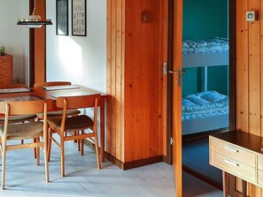 A room with a wooden desk, chairs, a bunk bed, and a wardrobe.