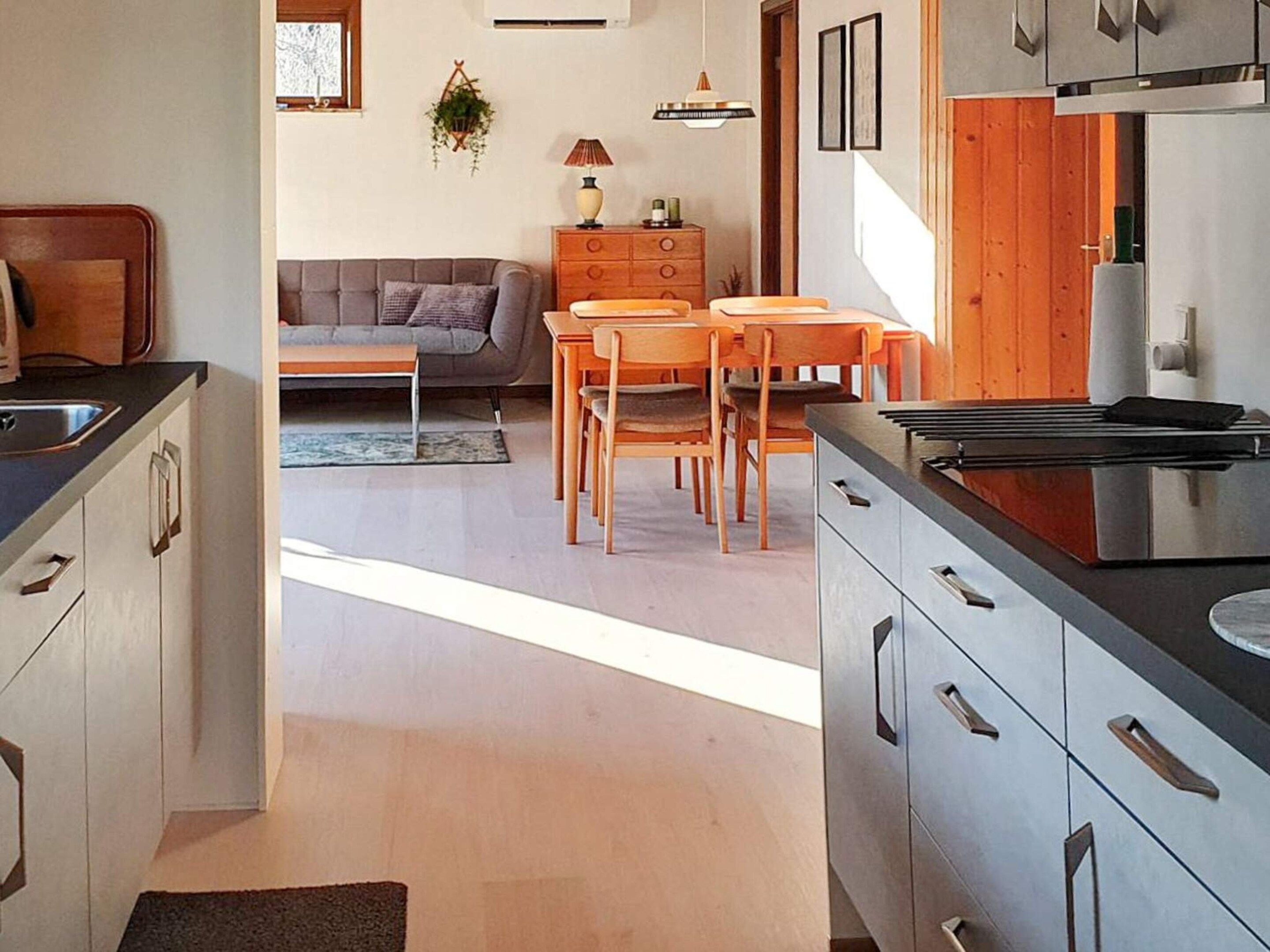 Una cocina moderna con comedor, armarios de madera y un sofá gris.